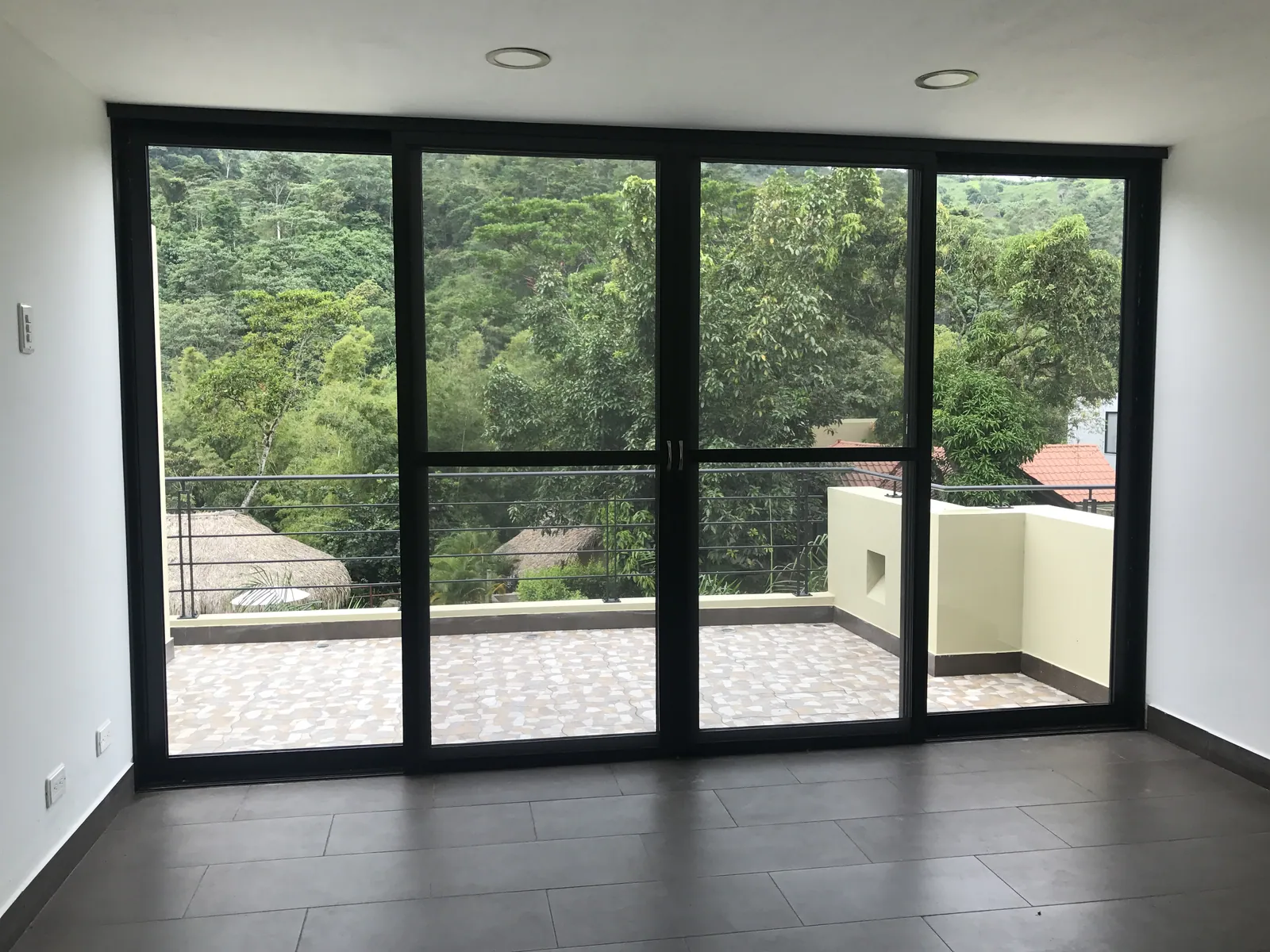 Sala abierta al jardín a través de una puerta corrediza de gran formato en aluminio negro, fabricada por ALUGANT