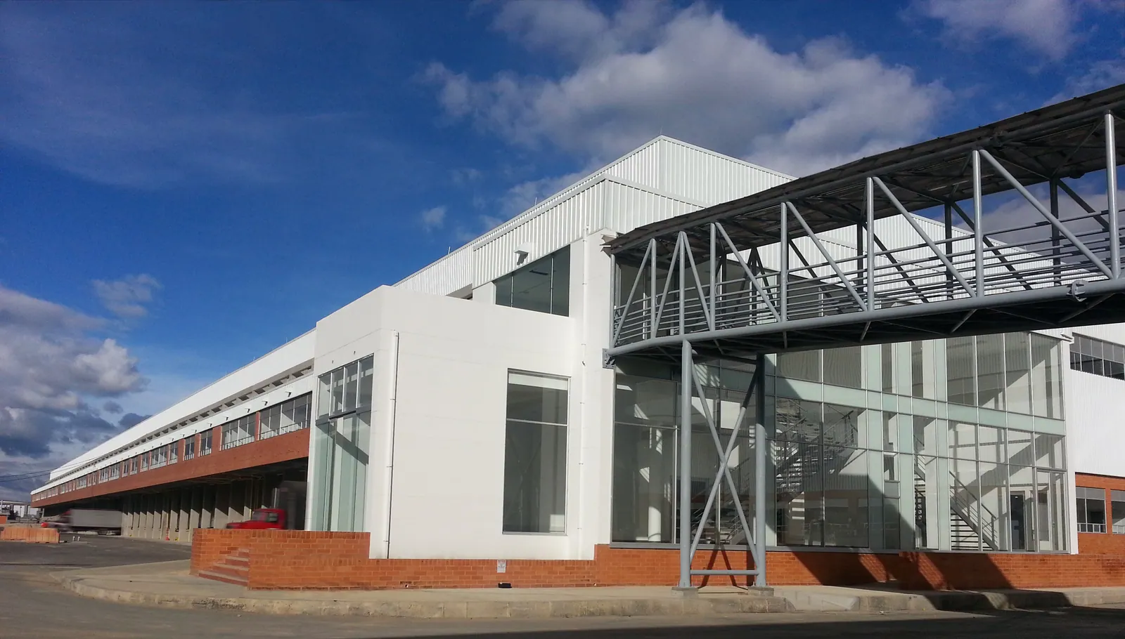 Belcorp: Fachada acristalada para planta industrial. Grandes ventanas continuas sobre estructura metálica.