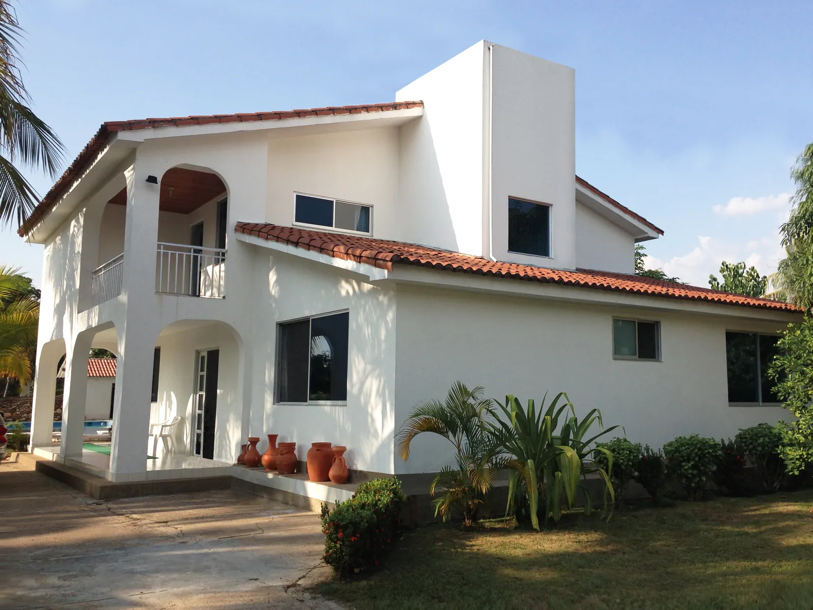 Villa Gloria: Ventanería y marquesina en policarbonato para una casa de clima cálido: ventilación cruzada y cubierta de acceso protegida del sol.